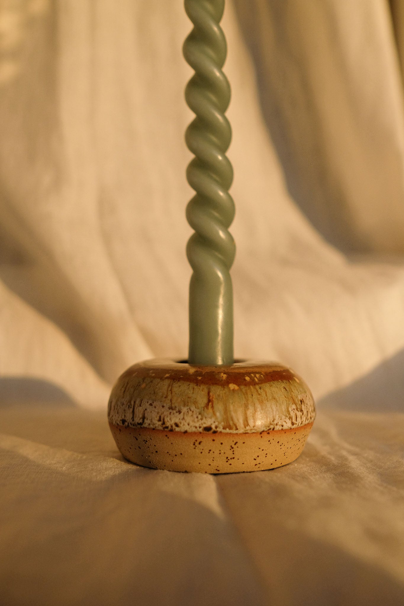 Détail d’un bougeoir donut en grès artisanal français, aux nuances caramel et miel, façonné et émaillé à la main, compatible avec une bougie standard.