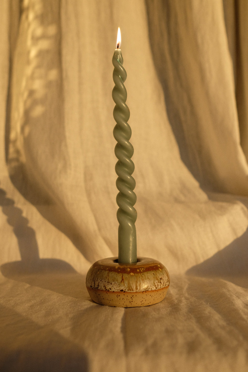 Bougeoir donut en grès artisanal émaillé aux nuances miel et caramel, avec chandelle torsadée, pièce unique façonnée à la main en France.