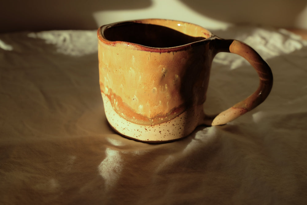 Détail d’un mug en grès artisanal aux nuances café et caramel, finition brillante et base brute, collection Détails x Ollaemporium